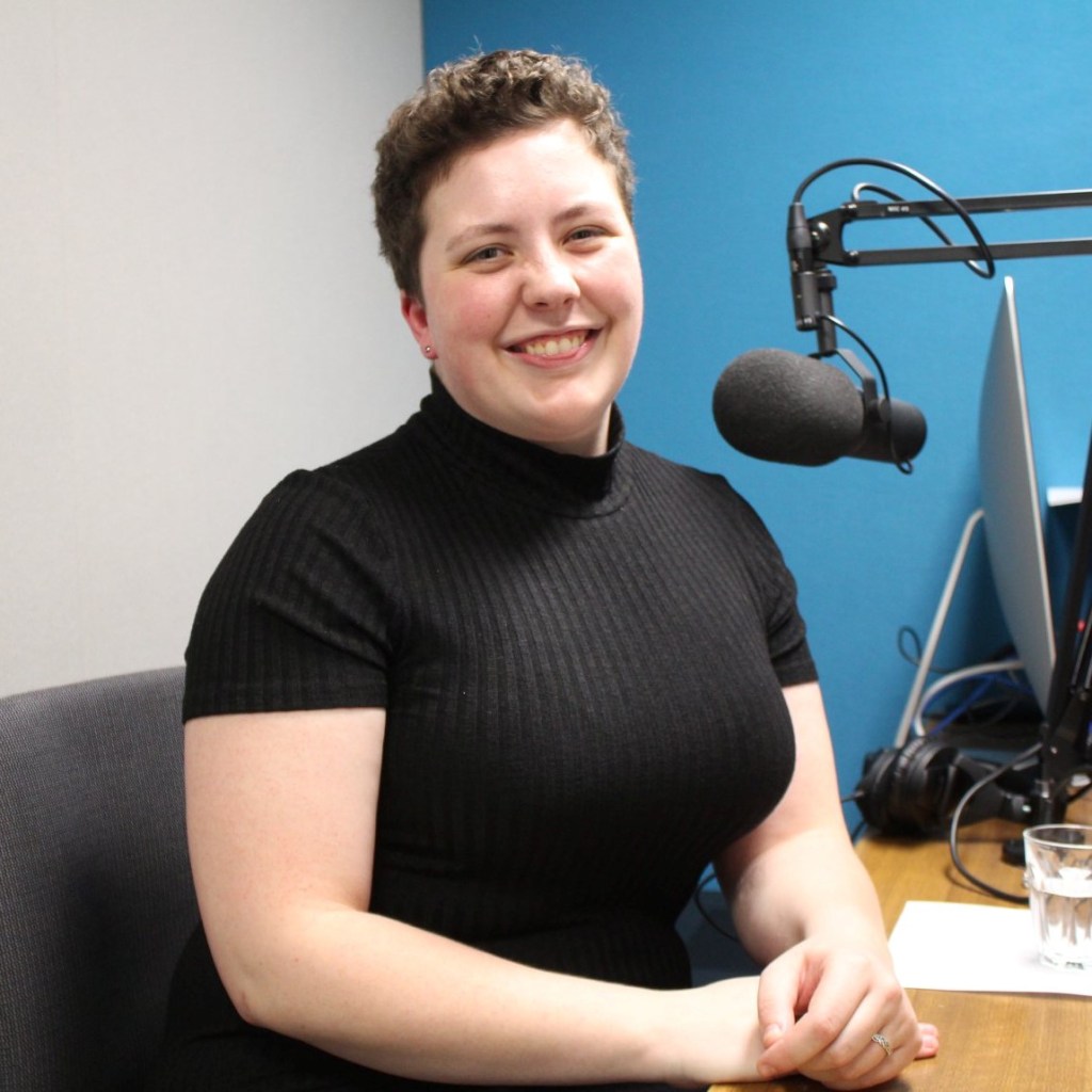 A photograph of Sophia on a white and blue background with a professional microphone clearly visible.